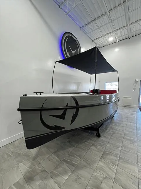 The Image of 2023 Vision Marine Technologies Volt 180 boat displayed indoors with sleek design and canopy. - 0