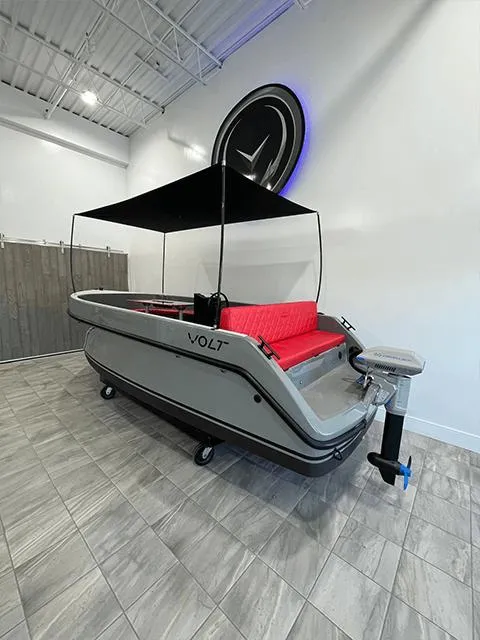 Slide: The Image of 2023 Vision Marine Technologies Volt 180 boat with canopy and red seating in showroom. - 1