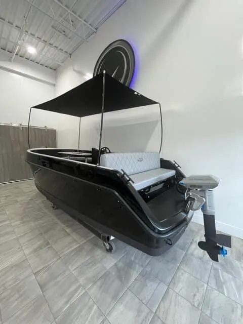 Slide: The Image of 2023 Vision Marine Technologies Volt 180 boat with canopy in showroom. - 2