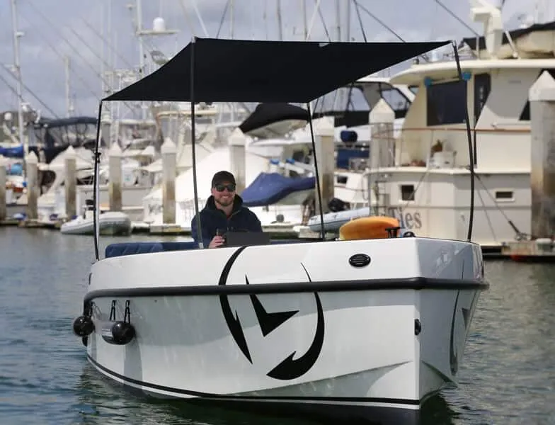Slide: The Image of 2023 Vision Marine Technologies Volt 180 boat docked at marina with canopy. - 2