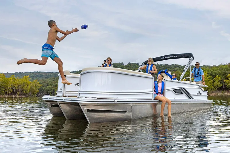 Slide: The Image of Manufacturer Provided Image: A boy jumps off a 2026 SunCatcher Fusion 324SL pontoon boat on a lake. - 11