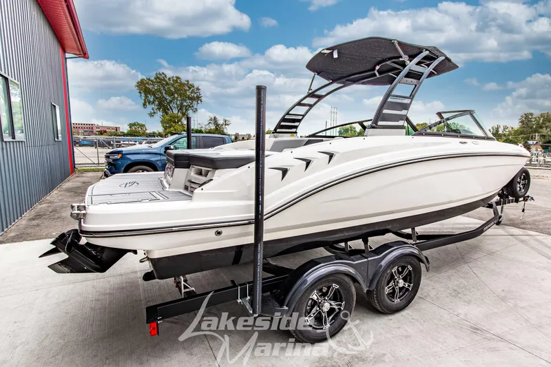 Slide: The Image of 2025 Chaparral 23 SSi boat on trailer at Lakeside Marina, under a clear sky. - 3
