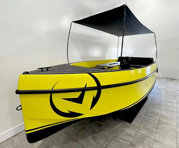 The Image of 2023 Vision Marine Technologies Volt 180, bright yellow electric boat with canopy, indoor display. - 0