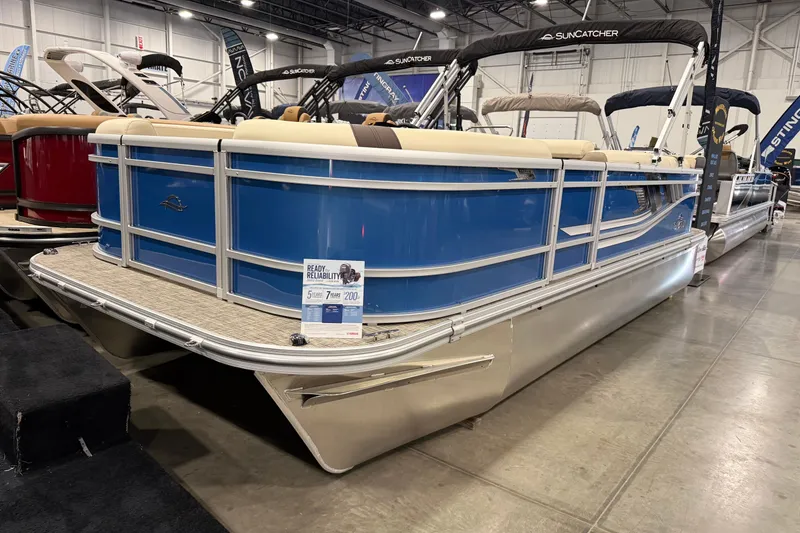 The Image of 2026 SunCatcher Select 20C pontoon boat displayed indoors, featuring blue exterior and beige seating. - 0