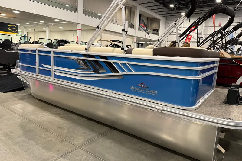 Slide: The Image of 2026 SunCatcher Select 20C pontoon boat in showroom, featuring blue exterior and sleek design. - 2