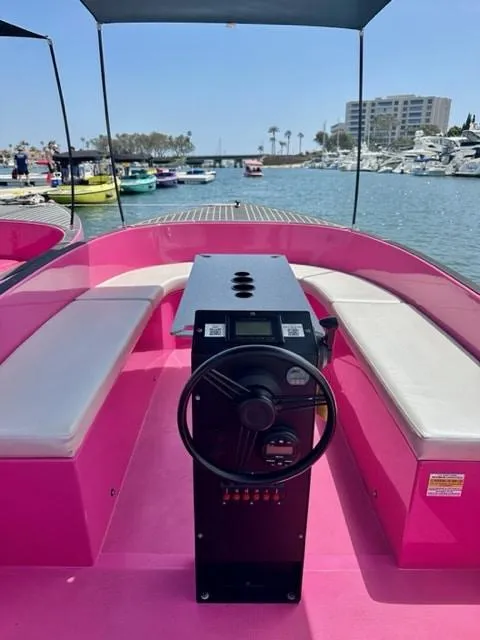 Slide: The Image of 2023 Vision Marine Technologies Volt 180, pink electric boat interior with white seating, docked in marina. - 3