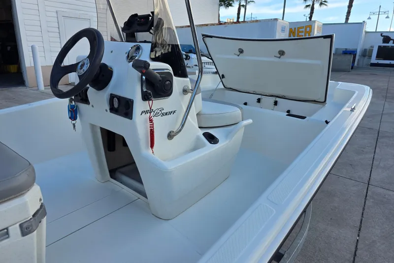 Slide: The Image of 2022 Mako Pro Skiff 15 CC boat interior with steering console and open storage compartment. - 3