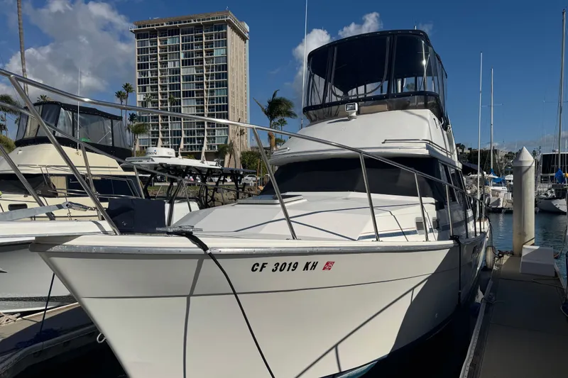 Slide: The Image of 1987 Bayliner 3270 Motoryacht docked at marina, with high-rise building in background. - 2