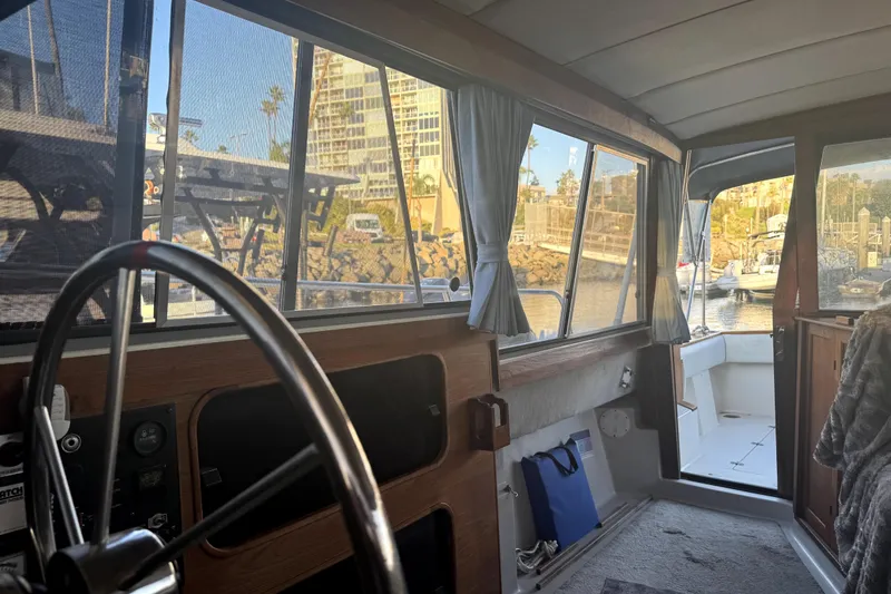 Slide: The Image of Interior view of 1987 Bayliner 3270 Motoryacht, featuring helm and marina backdrop. - 25