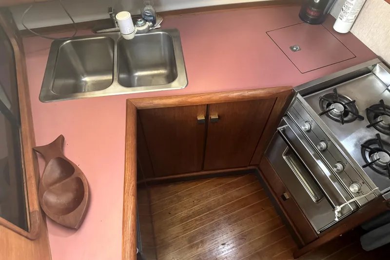 Slide: The Image of 1987 Bayliner 3270 Motoryacht kitchen with dual sink, stove, and wooden cabinetry. - 30
