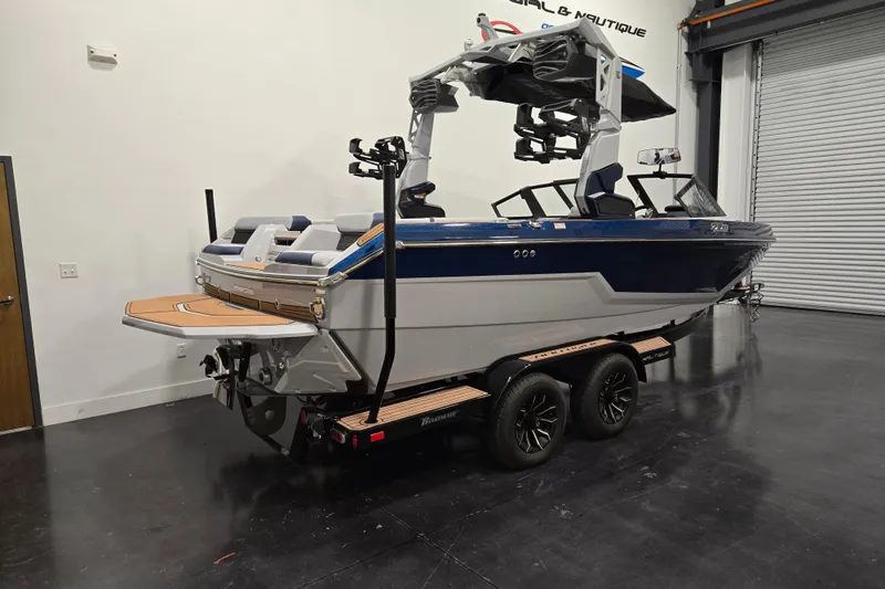 Slide: The Image of 2026 Nautique Super Air Nautique GS20 boat in showroom, blue and white design, on trailer. - 2