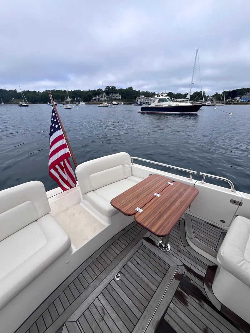 Slide: The Image of 2014 MJM 36z Downeast boat with American flag, wooden deck, and scenic harbor view. - 35