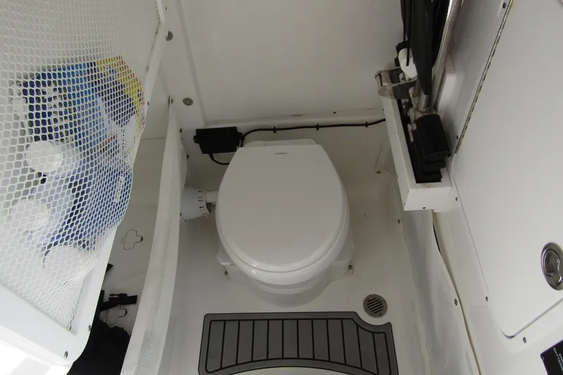 Slide: The Image of 2025 Sea Hunt Ultra 275 SE boat bathroom with toilet and storage net. - 19