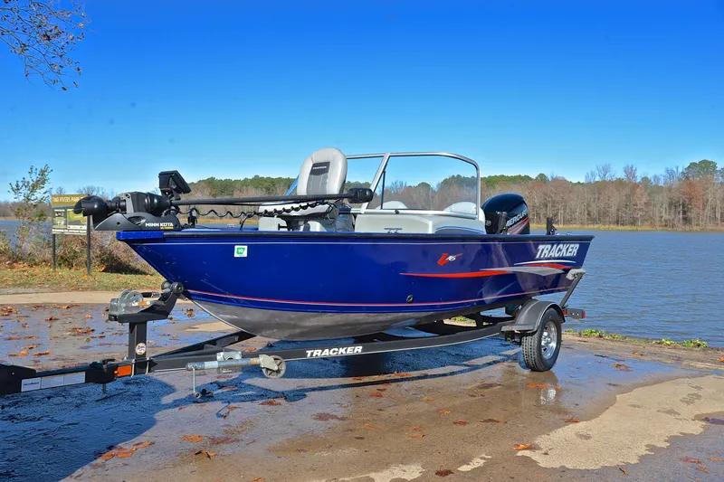 Slide: The Image of 2017 Tracker Pro Guide V-16 WT boat on trailer by a lake under clear blue sky. - 10