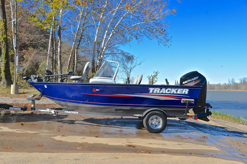 Slide: The Image of 2017 Tracker Pro Guide V-16 WT boat on trailer by a lake, surrounded by trees. - 11