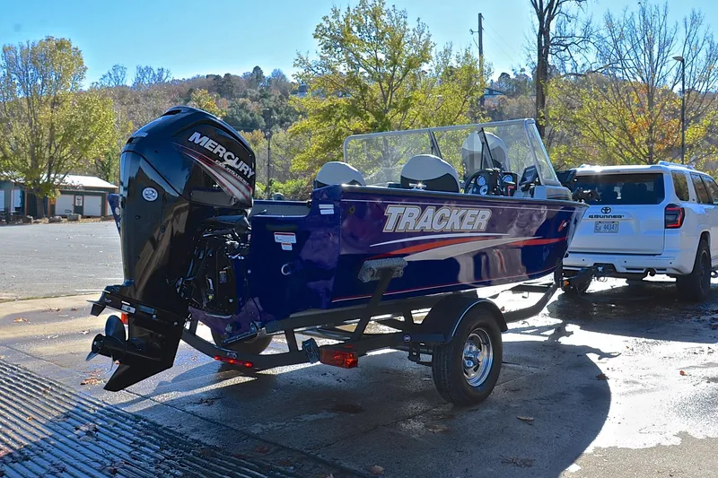 Slide: The Image of 2017 Tracker Pro Guide V-16 WT boat on trailer, parked near trees. - 14