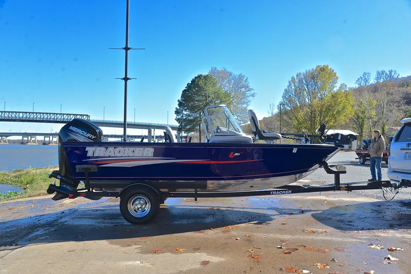Slide: The Image of 2017 Tracker Pro Guide V-16 WT boat on trailer by riverside, clear sky background. - 15