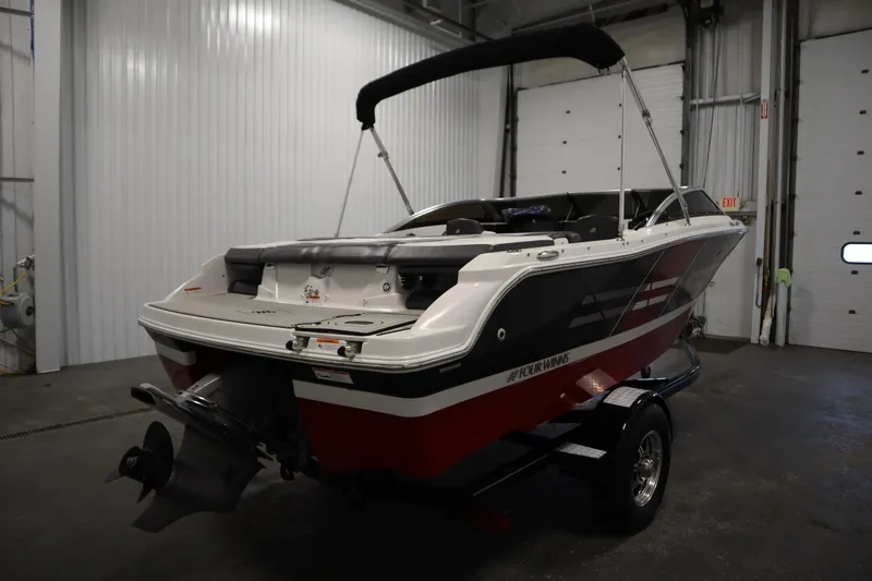 Slide: The Image of 2018 Four Winns H190 boat in a garage, featuring a sleek design and bimini top. - 5