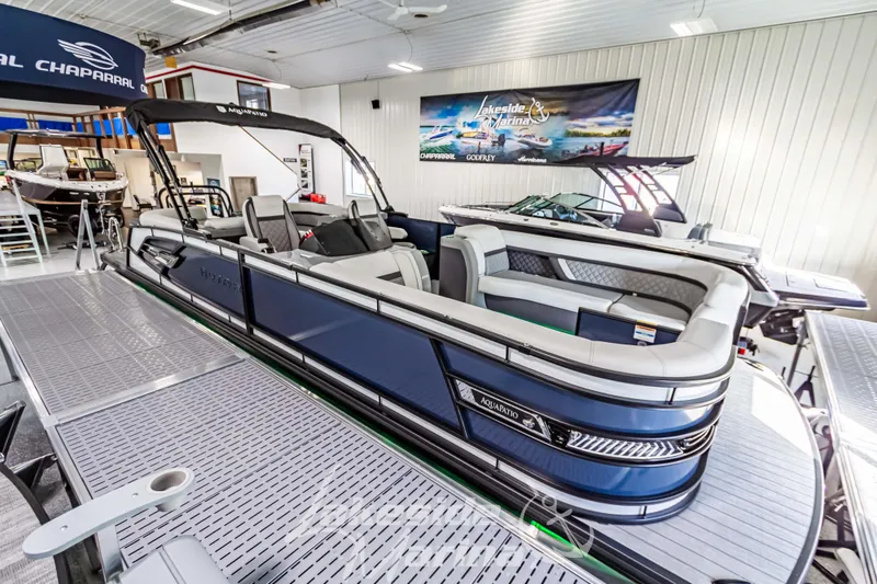 Slide: The Image of 2025 Godfrey AquaPatio 255 SBC pontoon boat in showroom, sleek design, luxury seating. - 18