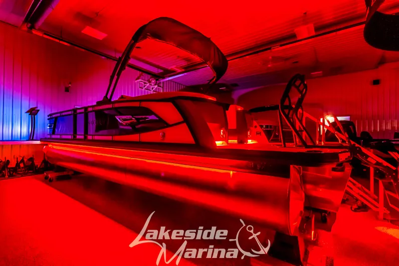 Slide: The Image of 2025 Godfrey AquaPatio 255 SBC boat in vibrant red lighting at Lakeside Marina. - 2