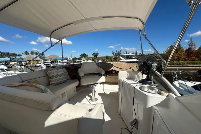 Slide: The Image of 2001 Carver 396 Motor Yacht deck with seating, fan, and marina view under clear skies. - 7