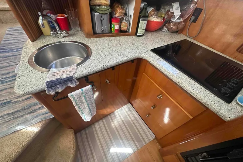 Slide: The Image of 2001 Carver 396 Motor Yacht kitchen with sink, stovetop, and storage cabinets. - 18