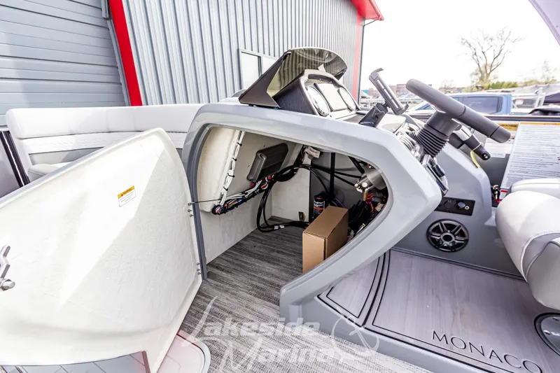 Slide: The Image of 2025 Godfrey Monaco 235 SB boat helm with open storage compartment and visible wiring. - 19