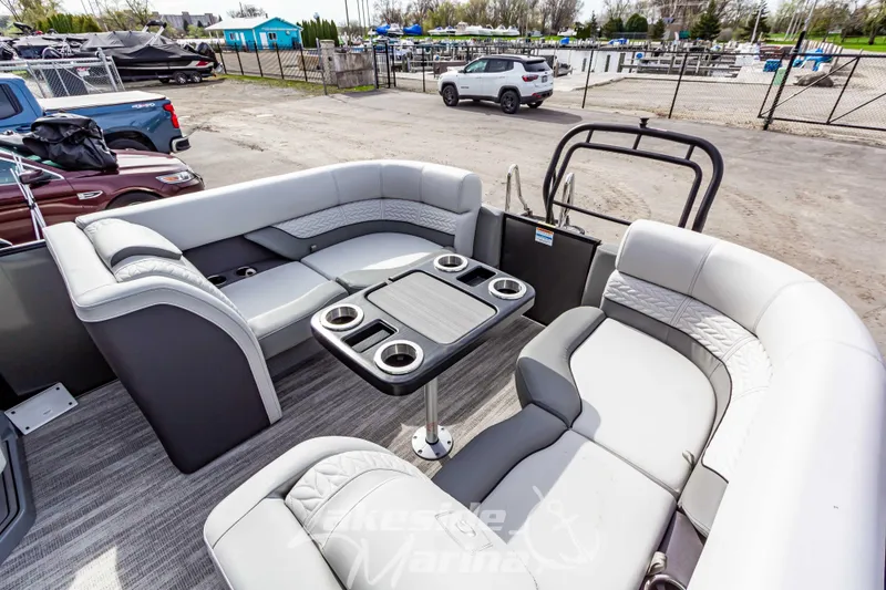 Slide: The Image of 2025 Godfrey Monaco 235 SB pontoon boat with luxurious seating and cup holders, docked at marina. - 25