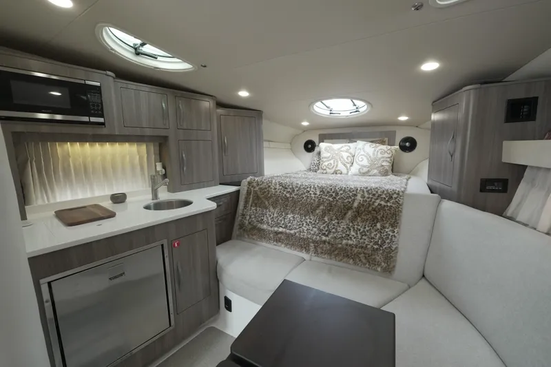 Slide: The Image of 2021 Regal 33 XO yacht interior with kitchenette, microwave, sink, and cozy sleeping area. - 16