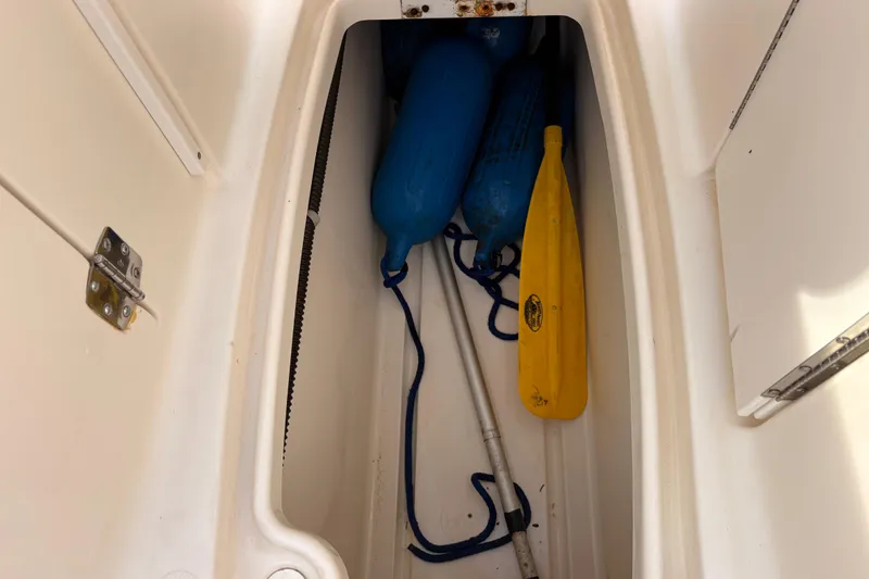 Slide: The Image of Storage compartment in a 2008 Hurricane SunDeck 2000 OB with blue fenders and a yellow paddle. - 12