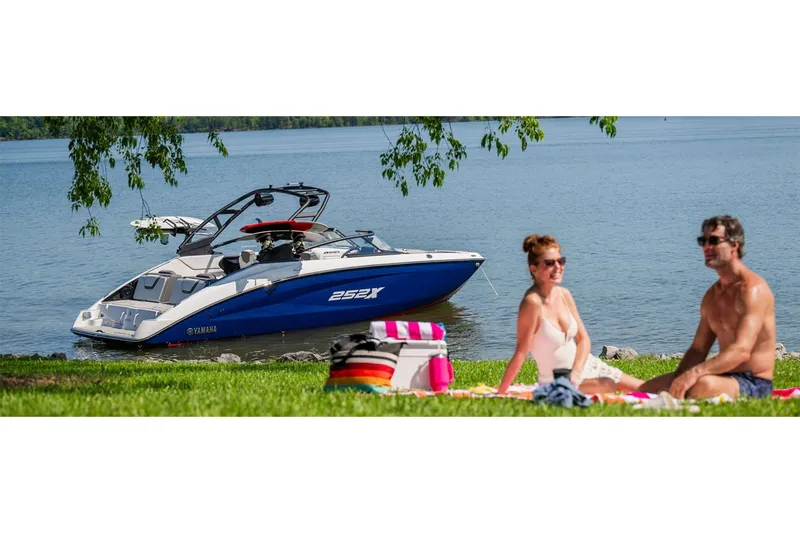 Slide: The Image of 2025 Yamaha Boats 252XE on a lake with people relaxing on the shore. - 9
