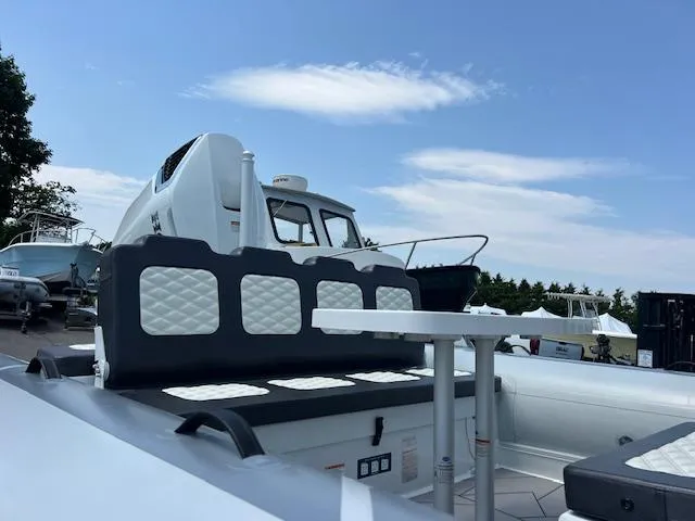 Slide: The Image of 2024 Highfield Sport 800 boat with cushioned seating, docked under a clear blue sky. - 15