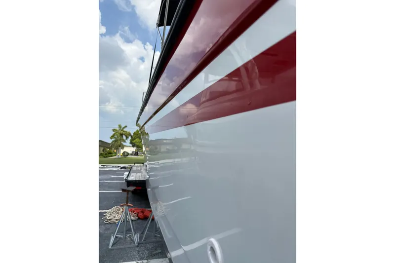 Slide: The Image of Side view of a 1997 Glacier Bay 260 Canyon Runner boat with red stripe detailing. - 4