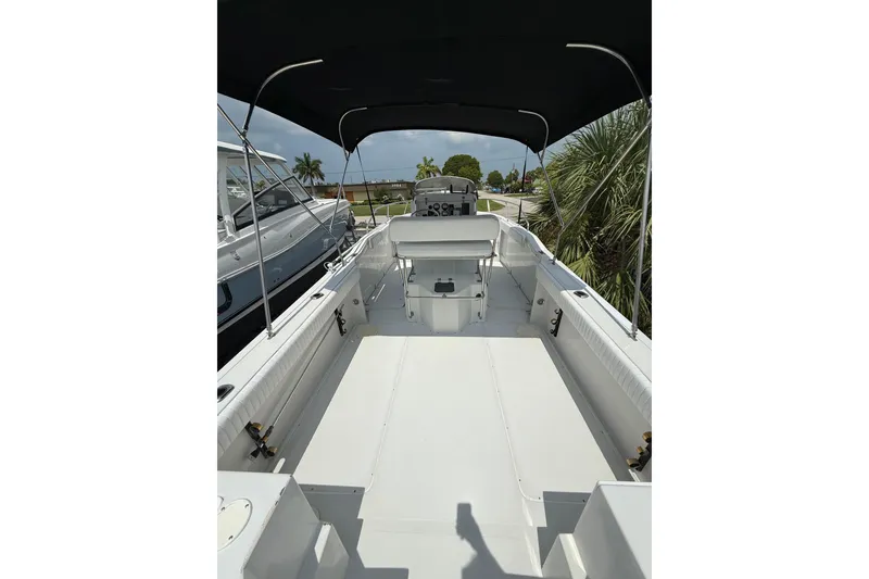 Slide: The Image of 1997 Glacier Bay 260 Canyon Runner boat interior with canopy, docked near palm trees. - 5