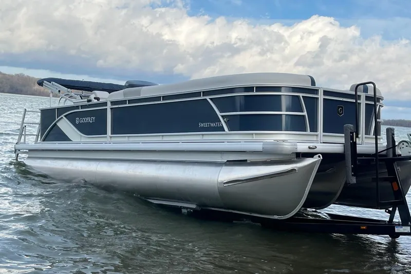 Slide: The Image of 2026 Sweetwater 2286C pontoon boat on water with cloudy sky backdrop. - 24