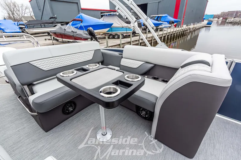 Slide: The Image of 2025 Godfrey Monaco 235 SFL boat interior with seating and table, docked at marina. - 25