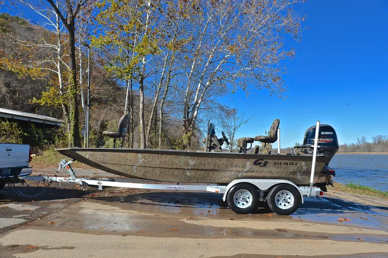 Slide: The Image of 2017 G3 Bay 20 DLX Camo boat on trailer by a lake, surrounded by trees. - 11