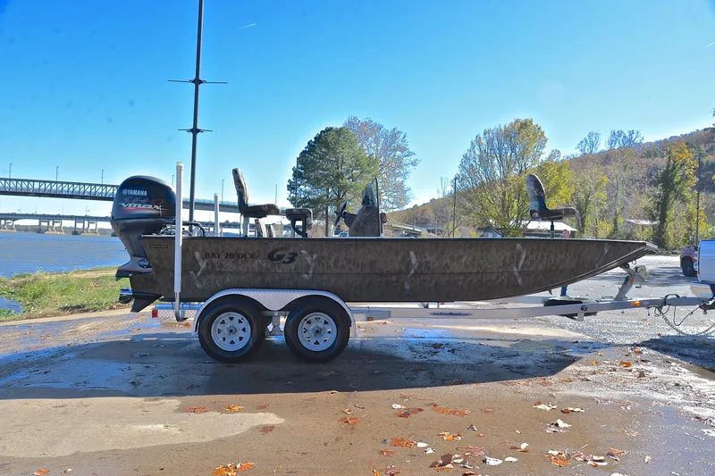 Slide: The Image of 2017 G3 Bay 20 DLX Camo boat on trailer by river, sunny day. - 15
