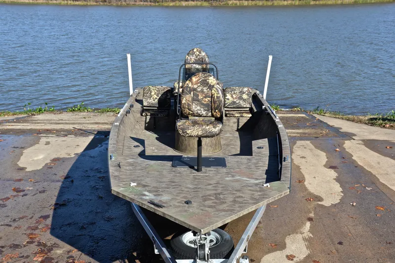Slide: The Image of 2017 G3 Bay 20 DLX Camo boat on trailer by a lake. - 17