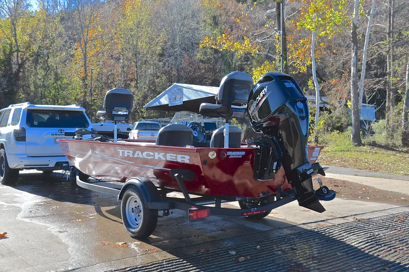 Slide: The Image of 2024 Tracker Pro 170 boat on trailer, parked near a wooded area. - 12