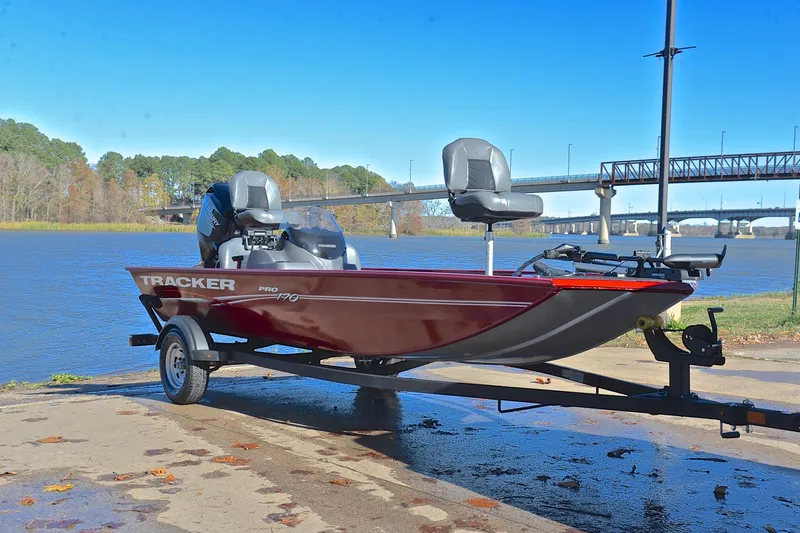 Slide: The Image of 2024 Tracker Pro 170 boat on trailer by a scenic river with bridge. - 16