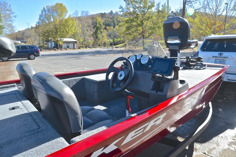 Slide: The Image of 2024 Tracker Pro 170 boat with red exterior and modern dashboard in a scenic parking area. - 19