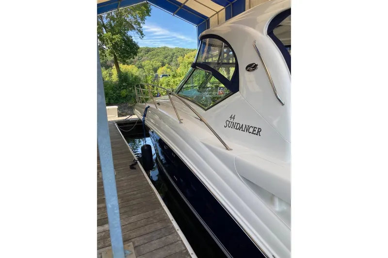 Slide: The Image of 2008 Sea Ray 44 Sundancer yacht docked under a canopy, surrounded by lush greenery. - 9