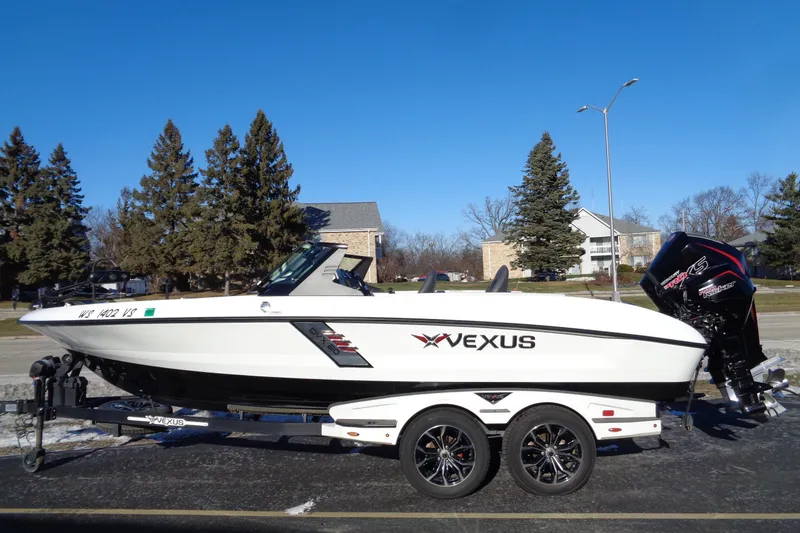 Slide: The Image of 2021 Vexus DVX20 boat on trailer, parked outdoors under clear blue sky. - 2