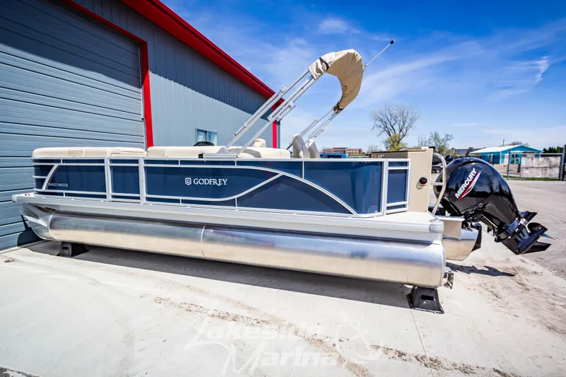 Slide: The Image of 2025 Godfrey Sweetwater 2286 FSX pontoon boat with Mercury outboard motor, docked outdoors. - 3