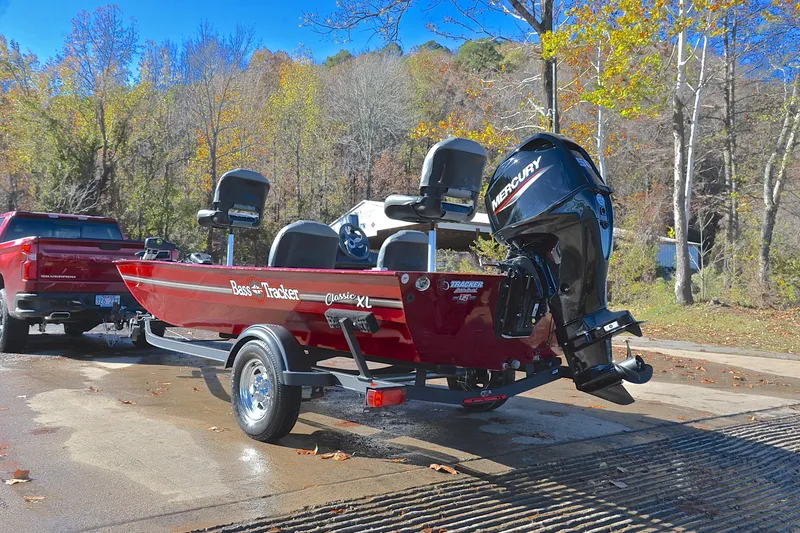 Slide: The Image of 2023 Bass Tracker Classic boat on trailer, parked near autumn trees. - 12