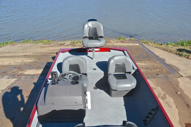 Slide: The Image of 2023 Bass Tracker Classic boat with gray seats, docked by a lake. - 24