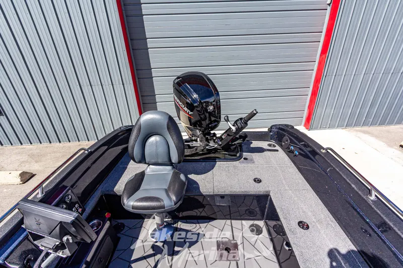 Slide: The Image of 2025 Recon 895 Tiller boat interior with seat and motor, parked near a garage. - 20