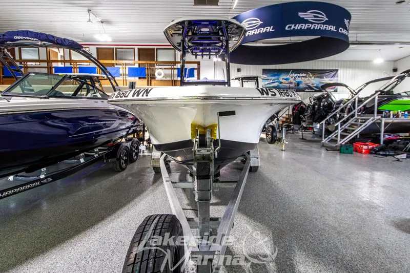 Slide: The Image of 2025 Tidewater 210 LXF boat on trailer in showroom, surrounded by other boats. - 10