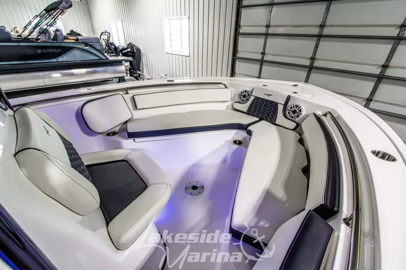 Slide: The Image of 2025 Tidewater 210 LXF boat interior with cushioned seating and speakers in a showroom. - 39